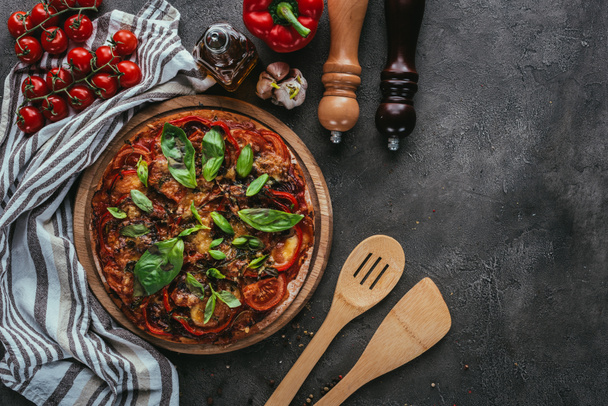 top view of pizza with wooden spatulas on concrete table - Foto, Bild