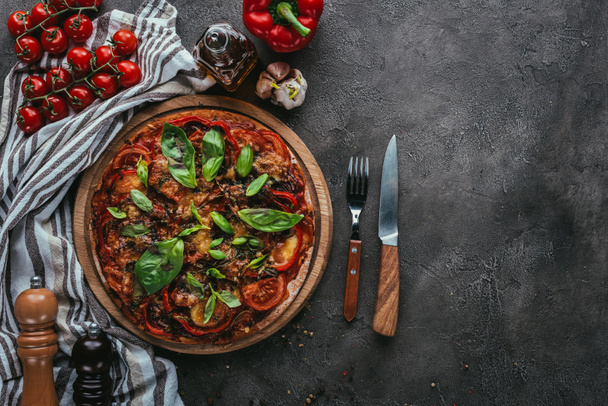 top view of delicious pizza with fork and knife on concrete table - Zdjęcie, obraz