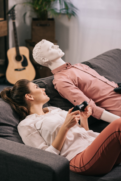 woman with manikin near by playing video game at home, loneliness concept - Photo, Image