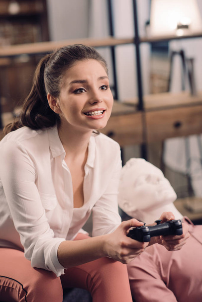 жінка з манікіном поблизу, граючи в відеогру вдома, концепція самотності
 - Фото, зображення