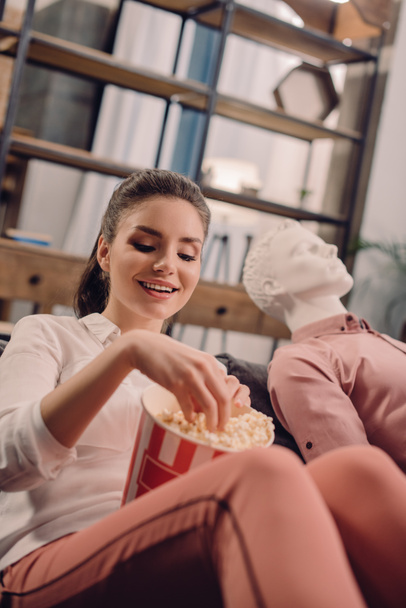 jonge vrouw eten popcorn met PROEFPOP in de buurt van door, unidirectionele liefde concept - Foto, afbeelding