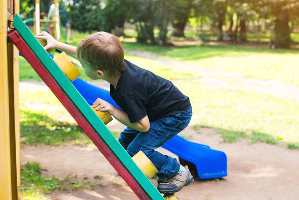 Petit garçon mignon s'amusant et grimpant sur une aire de jeux extérieure
. - Photo, image