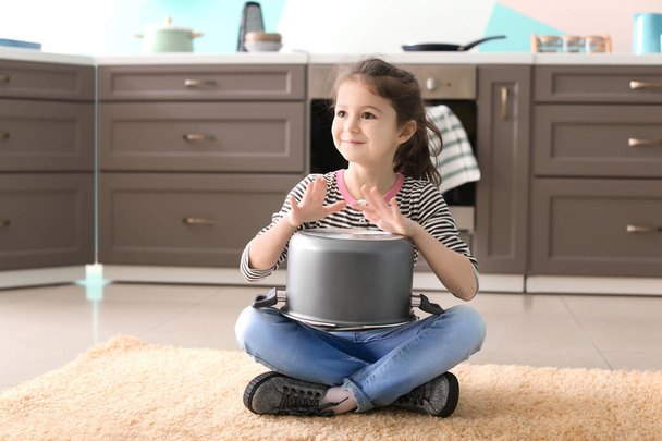 Cute little girl playing with saucepan as drum indoors - Foto, Imagen