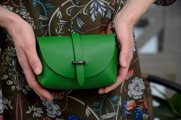 Elegant little green leather bag in the hands of a fashionista.  - Foto, imagen