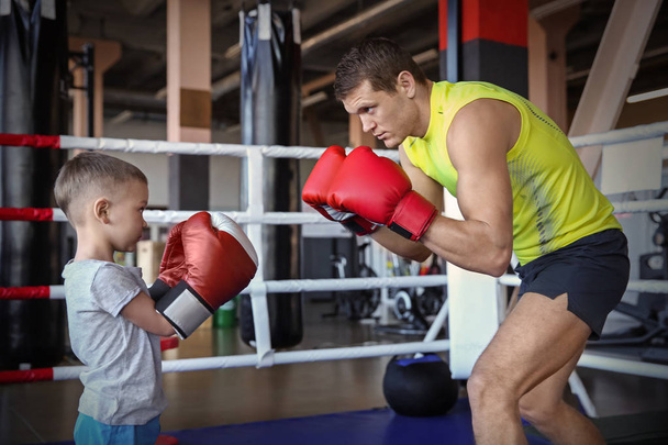 Little boy training with coach in boxing ring - Foto, afbeelding