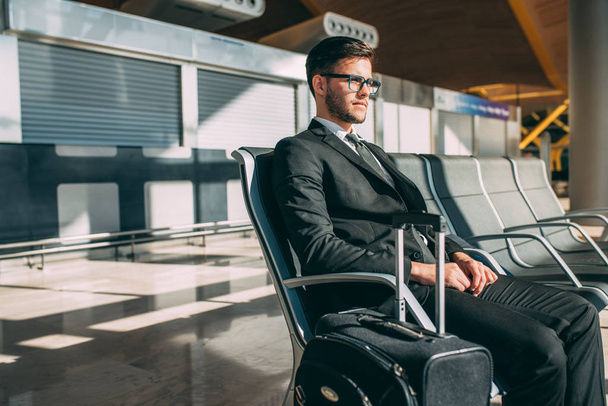Молодой бизнесмен, сидящий в аэропорту в ожидании рейса
 - Фото, изображение
