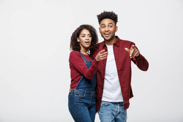 Молодые афроамериканцы в повседневной одежде смотрят в сторону и указывают пальцем. изолированные на белом фоне
 - Фото, изображение
