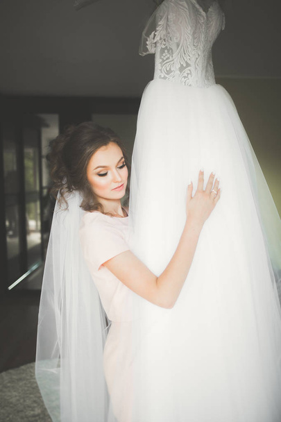 Gorgeous bride in robe posing and preparing for the wedding ceremony face in a room - Foto, immagini