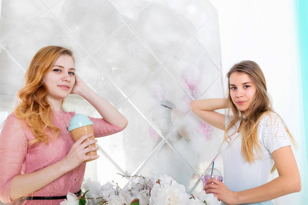 Dos chicas lindas en vestidos beben bebidas de tazas con tapas y t
 - Foto, Imagen
