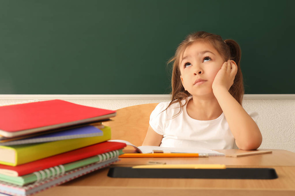 Nachdenkliches kleines Mädchen macht Hausaufgaben im Klassenzimmer - Foto, Bild