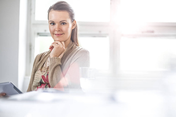 Портрет молодой предпринимательницы с помощью цифрового планшета в офисе
 - Фото, изображение