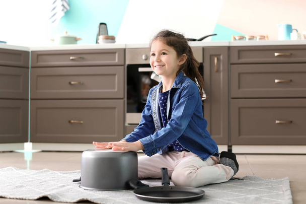 Cute little girl playing with saucepan as drum indoors - Fotó, kép