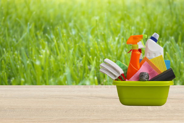 Spring cleaning concept with supplies against green nature blured background - Photo, Image