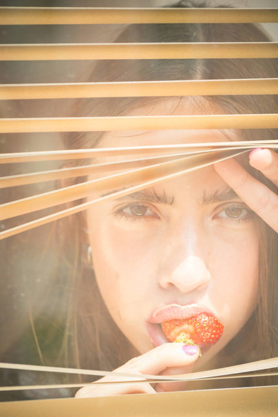 Young woman with berry in mouth - 写真・画像