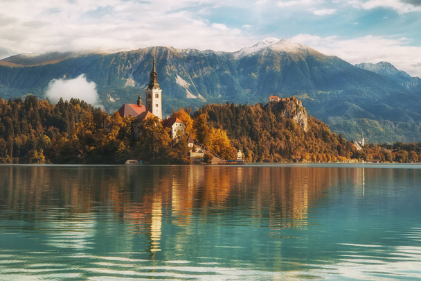 Mountainscape with chapel by the lake, clouds of fog in the back - Фото, изображение