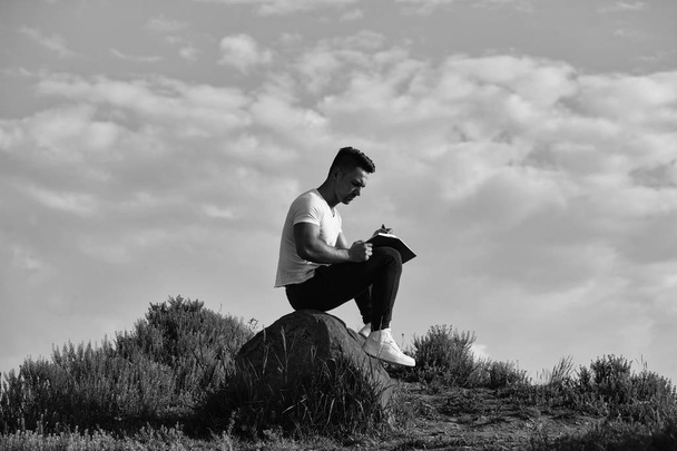 Pensive muscular man with book outdoor - Fotó, kép