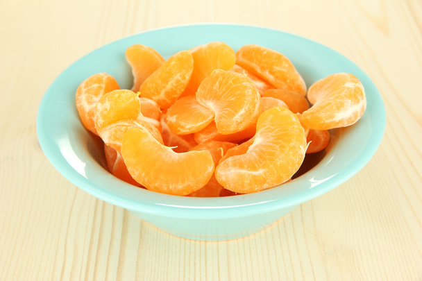 Tasty mandarine's slices in color bowl on light background - Foto, immagini