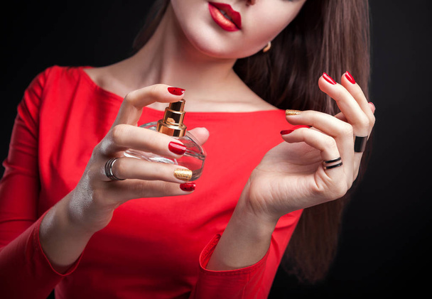 Femme appliquant du parfum sur son poignet sur fond noir
 - Photo, image