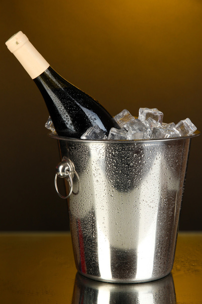 Bottle of wine in ice bucket on darck yellow background - Φωτογραφία, εικόνα