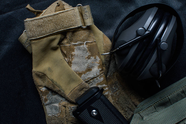Airrsoft pistool, oor bescherming hoofdtelefoon en bril ligt op zwarte achtergrond - Foto, afbeelding