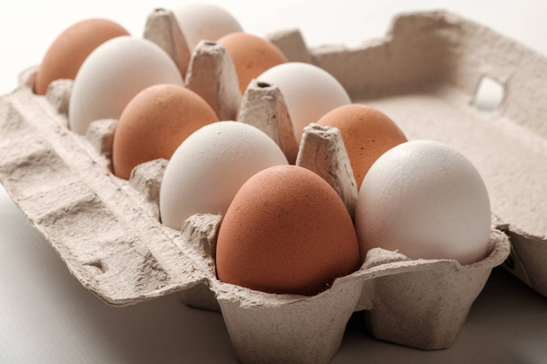 White and brown chicken eggs in a cardboard package. - Foto, Imagen