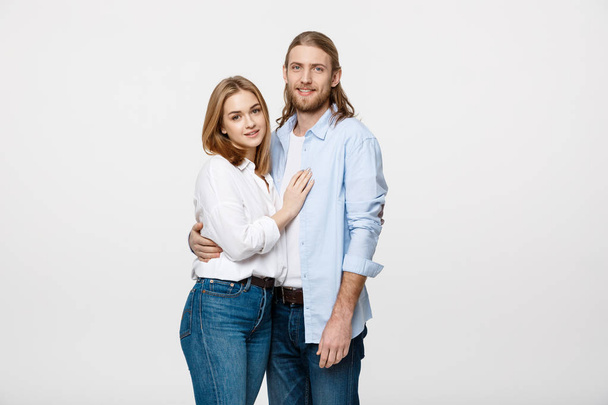 Portrait of cheerful young couple standing and hugging each other on isolated white background - Фото, изображение