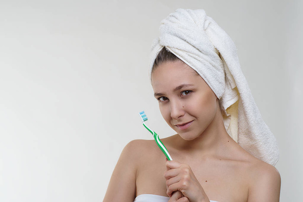 Happy lovely young woman with beautiful fresh skin, healthy look and wonderful smile in a towel posing with a tooth brush on white background. Spa wellness healthcare model photo shooting - Фото, изображение