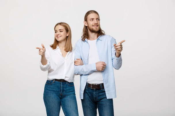 Portrait young happy couple love smiling embracing point finger to empty copy space, man and woman smile looking up, isolated over white background - Photo, Image