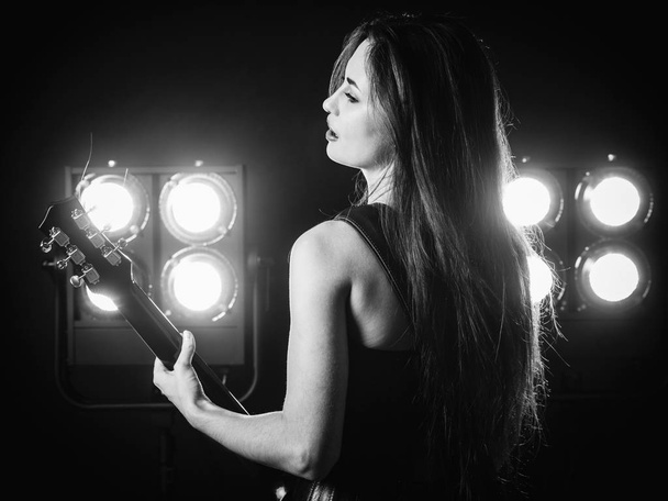 Young woman playing electric guitar on stage - Zdjęcie, obraz