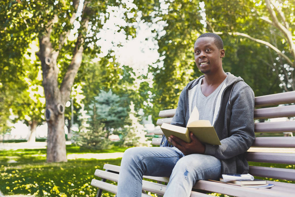 Estudiante afroamericano leyendo un libro al aire libre
 - Foto, imagen