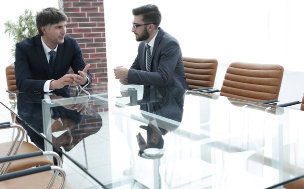 Two businessmen discussing tasks sitting at office table. - Fotó, kép