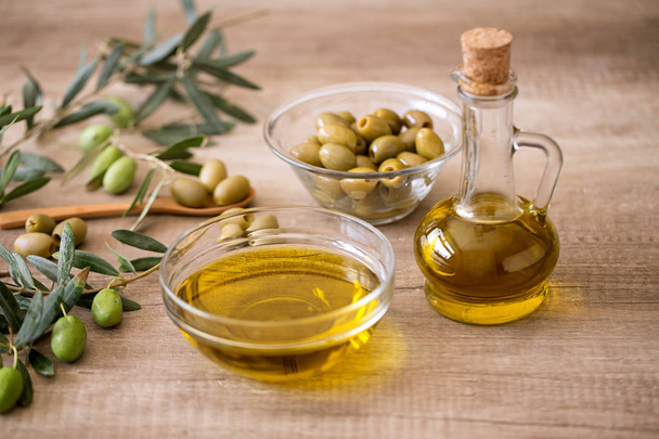 Extra virgin healthy Olive oil with olive on wooden background - Foto, afbeelding