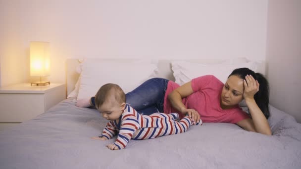 Втомилася мати лежить на ліжку, дивлячись на її дитину
 - Кадри, відео