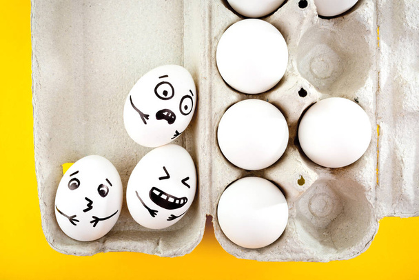 Huevos de Pascua con caras de dibujos animados dibujados en bandeja sobre fondo amarillo
. - Foto, Imagen