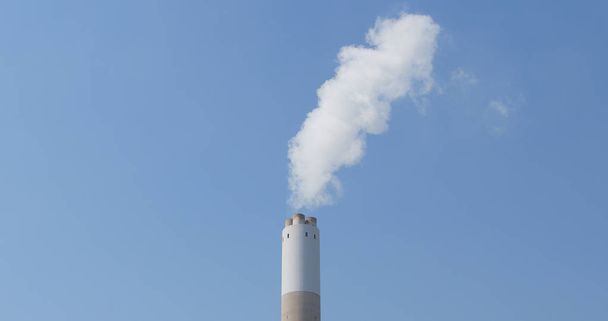 Ο καπνός από το εργοστάσιο πάνω από το γαλάζιο του ουρανού  - Φωτογραφία, εικόνα