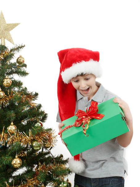 Happy boy in santa hat surprised by christmas present - Fotografie, Obrázek