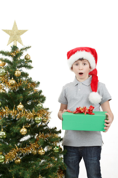glücklicher Junge mit Weihnachtsmütze von Weihnachtsgeschenk überrascht - Foto, Bild