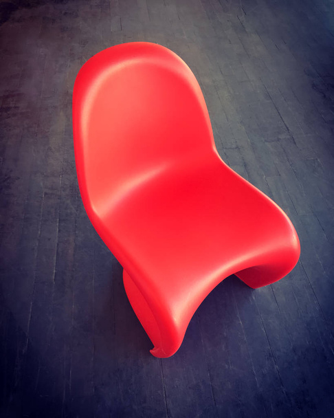 Red plastic chair on dark wooden floor - Foto, Imagem