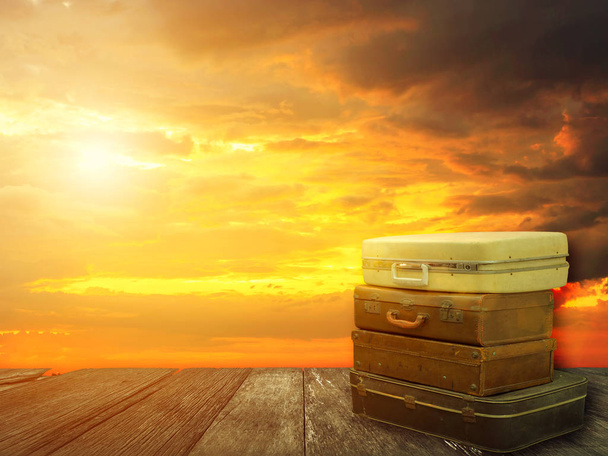 Bagagem de couro empilhada na prancha de madeira com fundo céu por do sol
 - Foto, Imagem