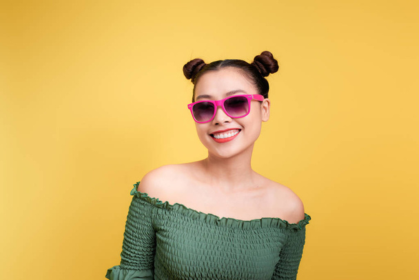 stylische junge Frau mit Sonnenbrille vor gelbem Hintergrund. - Foto, Bild