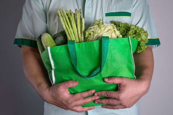 крупним планом рука тримає зелену продуктову сумку змішаного органічного сірого
 - Фото, зображення
