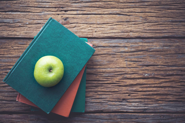 Green apple on books with wooden background. - Photo, Image