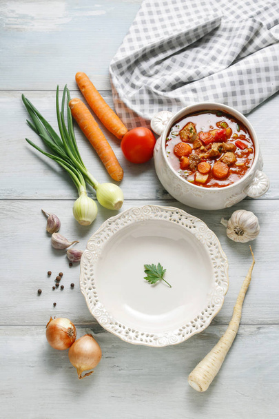 Empty plate and bowl of goulash. Raw vegetables around - Fotó, kép