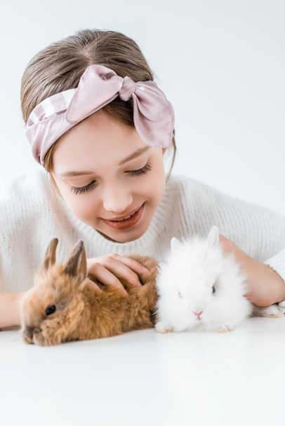 niño feliz jugando con adorables conejos peludos en blanco
  - Foto, imagen