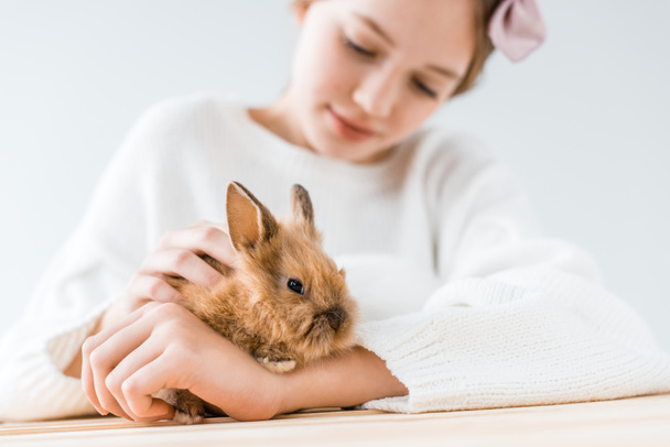 close-up view of smiling girl holding adorable furry rabbit on white  - Foto, immagini