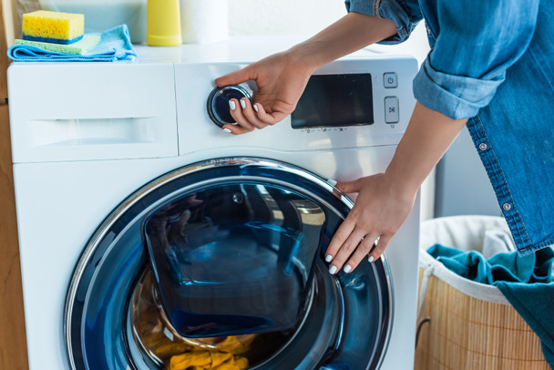 обрезанный снимок женщины с помощью стиральной машины дома
  - Фото, изображение