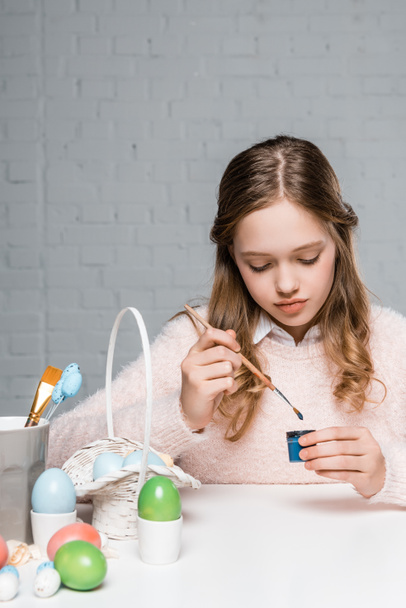 adorável menina pintando ovos de Páscoa à mesa
  - Foto, Imagem