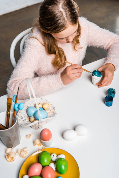 vista de ángulo alto de lindo niño enfocado pintura huevo de Pascua en la mesa
 - Foto, Imagen