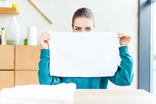 jovem mulher segurando toalha branca limpa e olhando para a câmera
 - Foto, Imagem