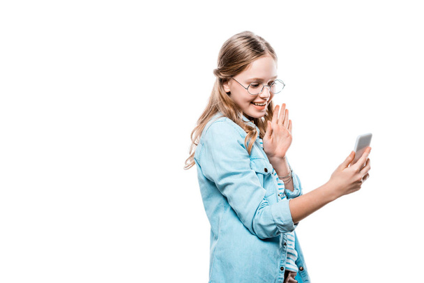 beautiful happy teenage girl in eyeglasses using smartphone isolated on white - Fotó, kép